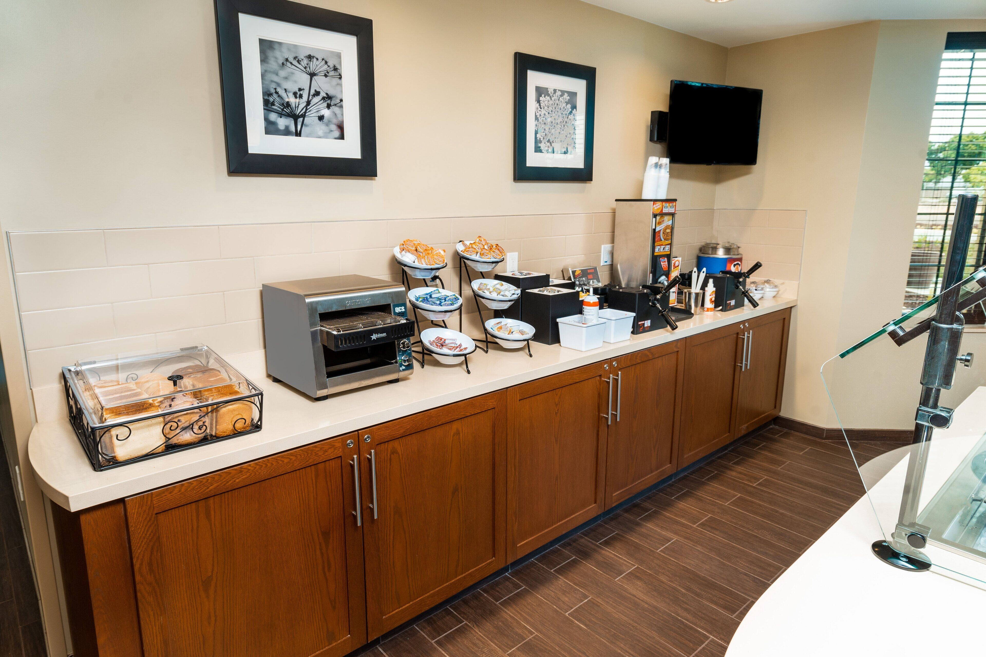 A kitchen with a coffee machine, a microwave, and a toaster. There are also bowls of food and a glass container on the counter.