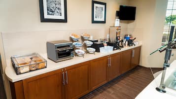 A kitchen with a coffee machine, a microwave, and a toaster. There are also bowls of food and a glass container on the counter.