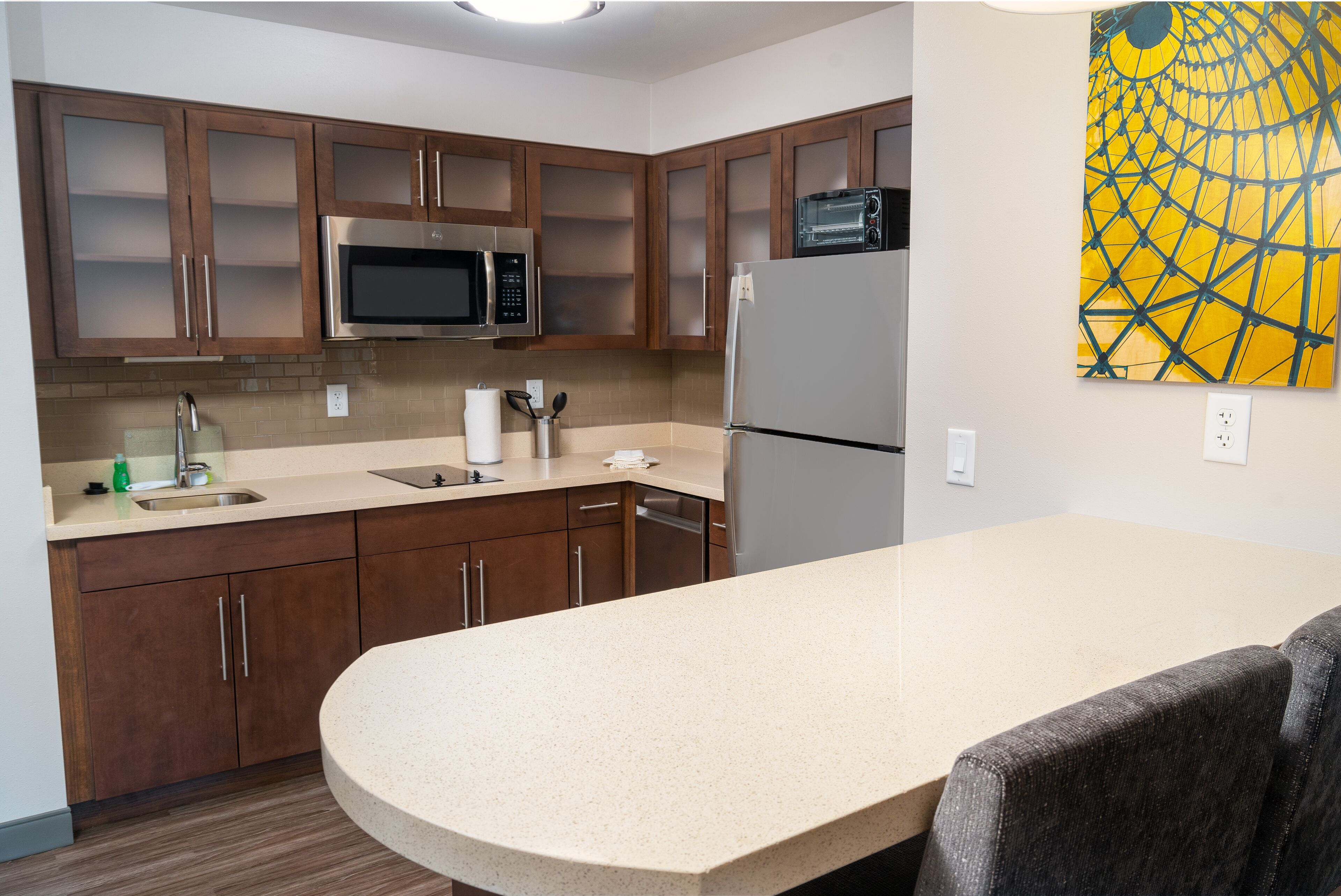 A modern kitchen with wooden cabinets, a microwave, a refrigerator, and a sink.