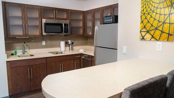 A modern kitchen with wooden cabinets, a microwave, a refrigerator, and a sink.