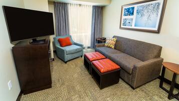 A living room with a flat-screen TV, two sofas, a coffee table, and a framed picture on the wall.