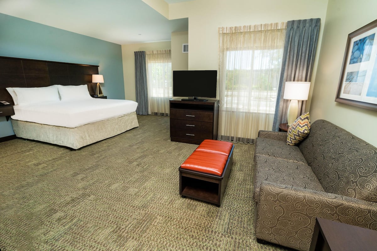 A hotel room with a bed, a TV, a sofa, and a small table.