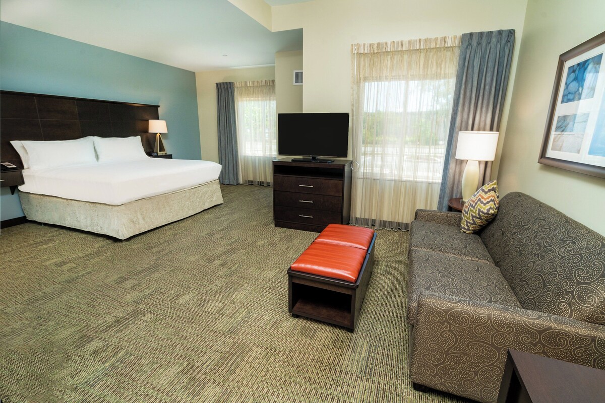 A hotel room with a bed, a TV, a sofa, and a small table.