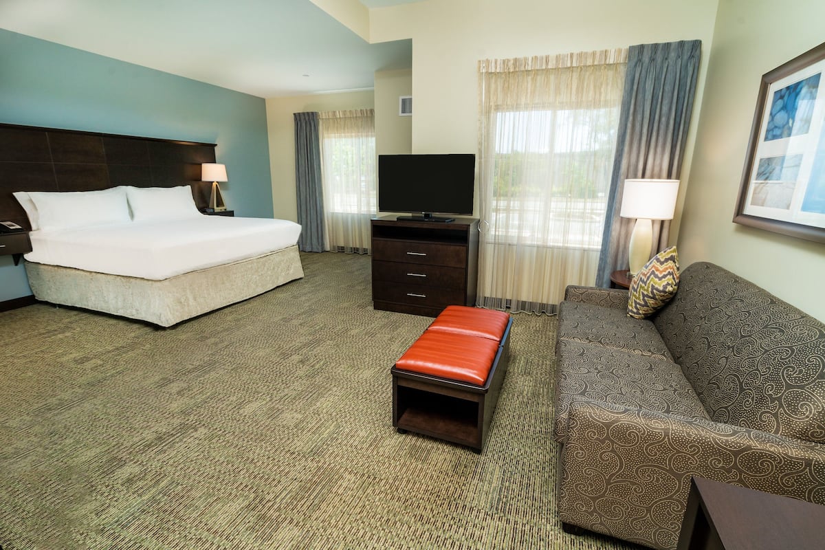 A hotel room with a bed, a TV, a sofa, and a small table.