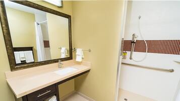 A bathroom with a sink, mirror, and shower.