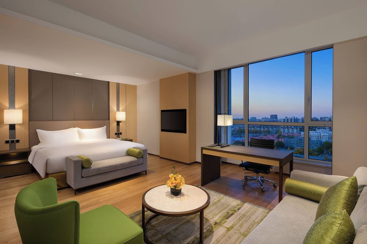 Een moderne hotelkamer met een groot bed, een bureau en uitzicht op de stad.