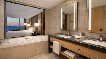 A modern hotel bathroom with two sinks, a large mirror, and a city view.