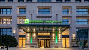 L’entrée d’un hôtel Holiday Inn & Suites, dotée d’un design moderne, avec un porche abrité et une enseigne lumineuse.