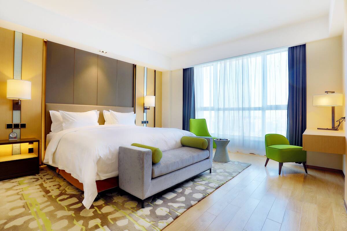 Een hotelkamer met een bed, een bureau, een stoel en een groot raam.