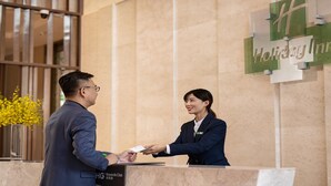 Un comptoir d’accueil d’hôtel avec une enseigne « Holiday Inn » et une autre indiquant le programme de fidélité.