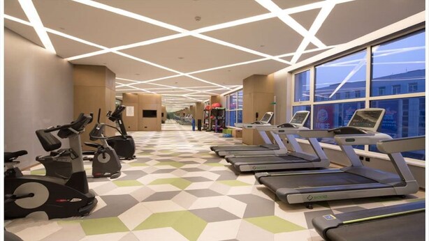 Un gimnasio con cintas de correr, bicicletas estáticas y máquinas elípticas.