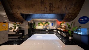 Eine moderne Hotelhalle mit einer Rezeption, einer Speiseausgabe und einem großen, weißen Bereich in der Mitte.