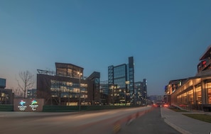 A modern building with a glass facade, a sign indicating an event, and a well-lit street. - Holiday Inn Express Beijing Shijingshan Parkview by IHG (Beijing)