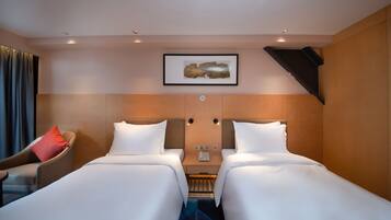 Une chambre d’hôtel avec deux lits, une table de chevet, une chaise et un tableau encadré au mur.