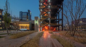 A modern building with a Starbucks Coffee on the ground floor, a staircase leading to upper levels, and a pathway in the foreground. - Holiday Inn Express Beijing Shijingshan Parkview by IHG (Beijing)