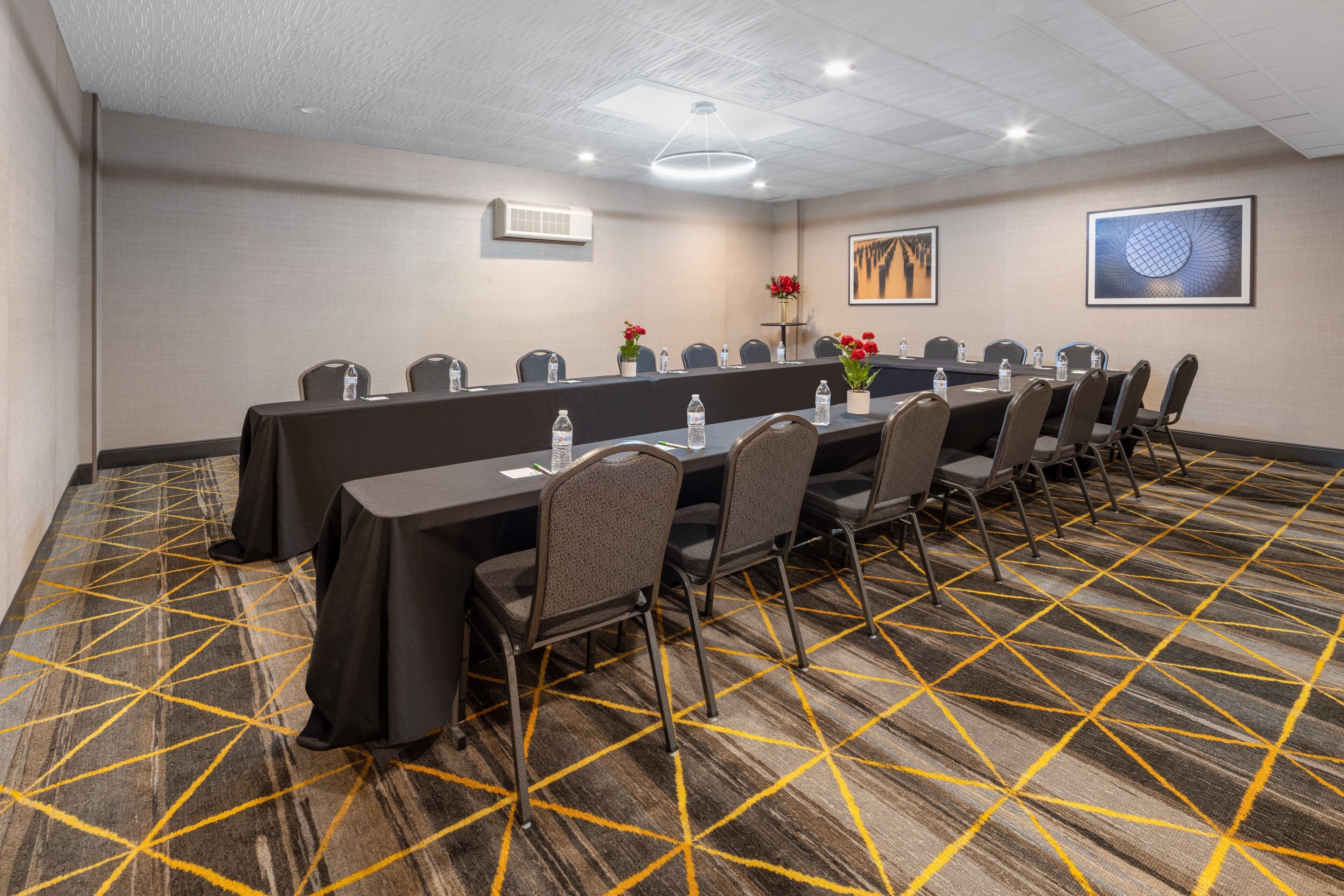 A conference room with a long table, chairs, and a patterned carpet.
