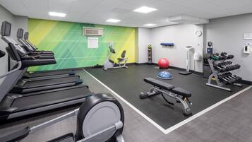 A fitness center with treadmills, an elliptical, a bench, a medicine ball, and dumbbells.