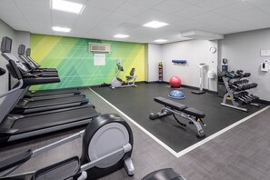 A fitness center with treadmills, an elliptical, a bench, a medicine ball, and dumbbells.
