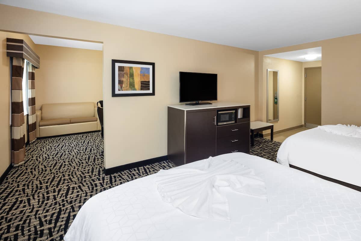 A hotel room with a bed, a TV, a desk, and a mirror.