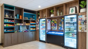 A well-organized snack and beverage area with refrigerated sections and shelves stocked with various snacks and drinks. - Holiday Inn Poughkeepsie by IHG (Poughkeepsie)