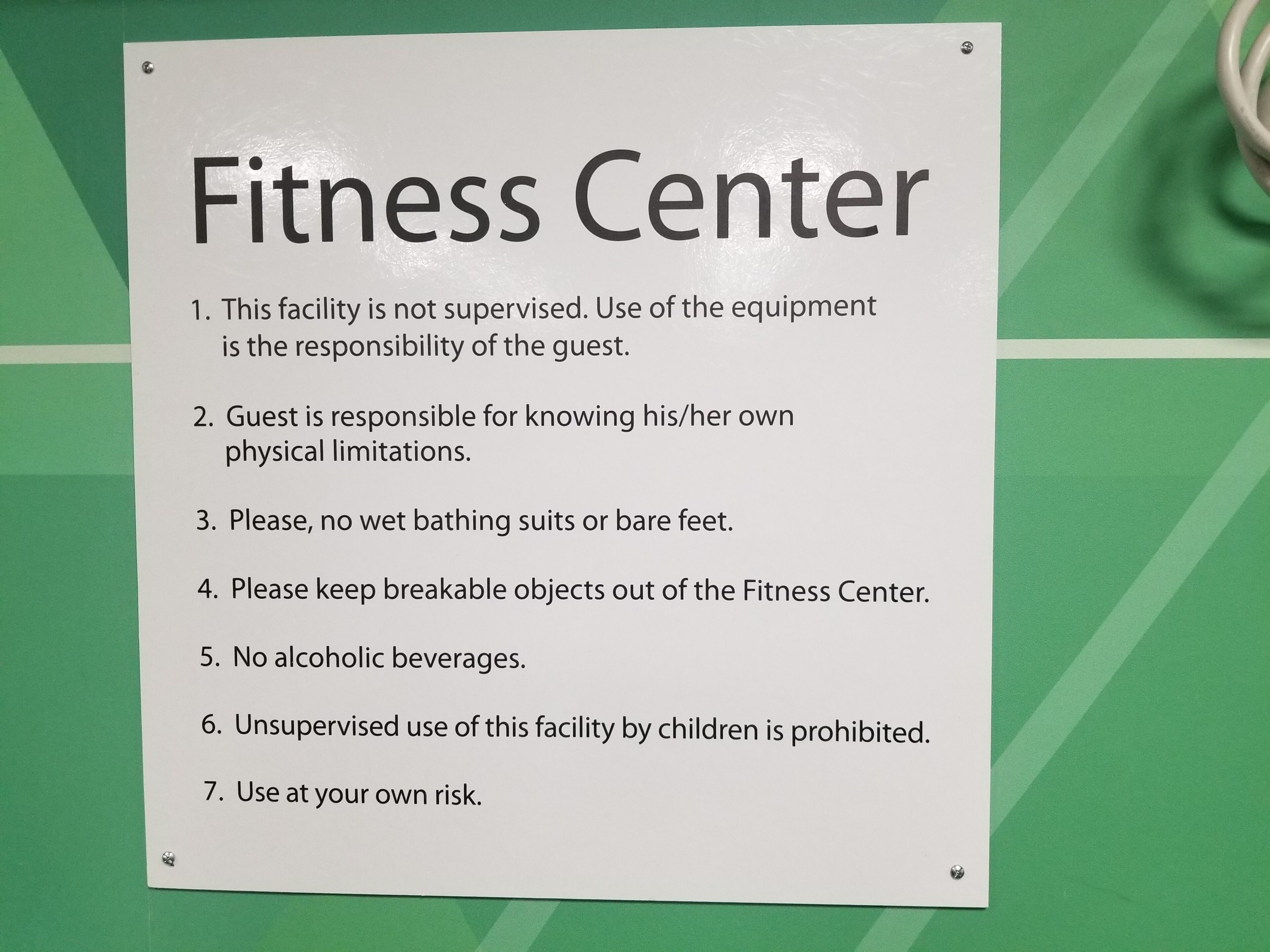 Letrero que enumera las normas para usar el gimnasio, incluyendo la supervisión y restricciones sobre ciertos objetos.