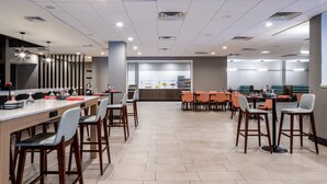 A modern restaurant with a long counter, multiple seating areas, and a visible kitchen in the background. - Holiday Inn Poughkeepsie by IHG (Poughkeepsie)