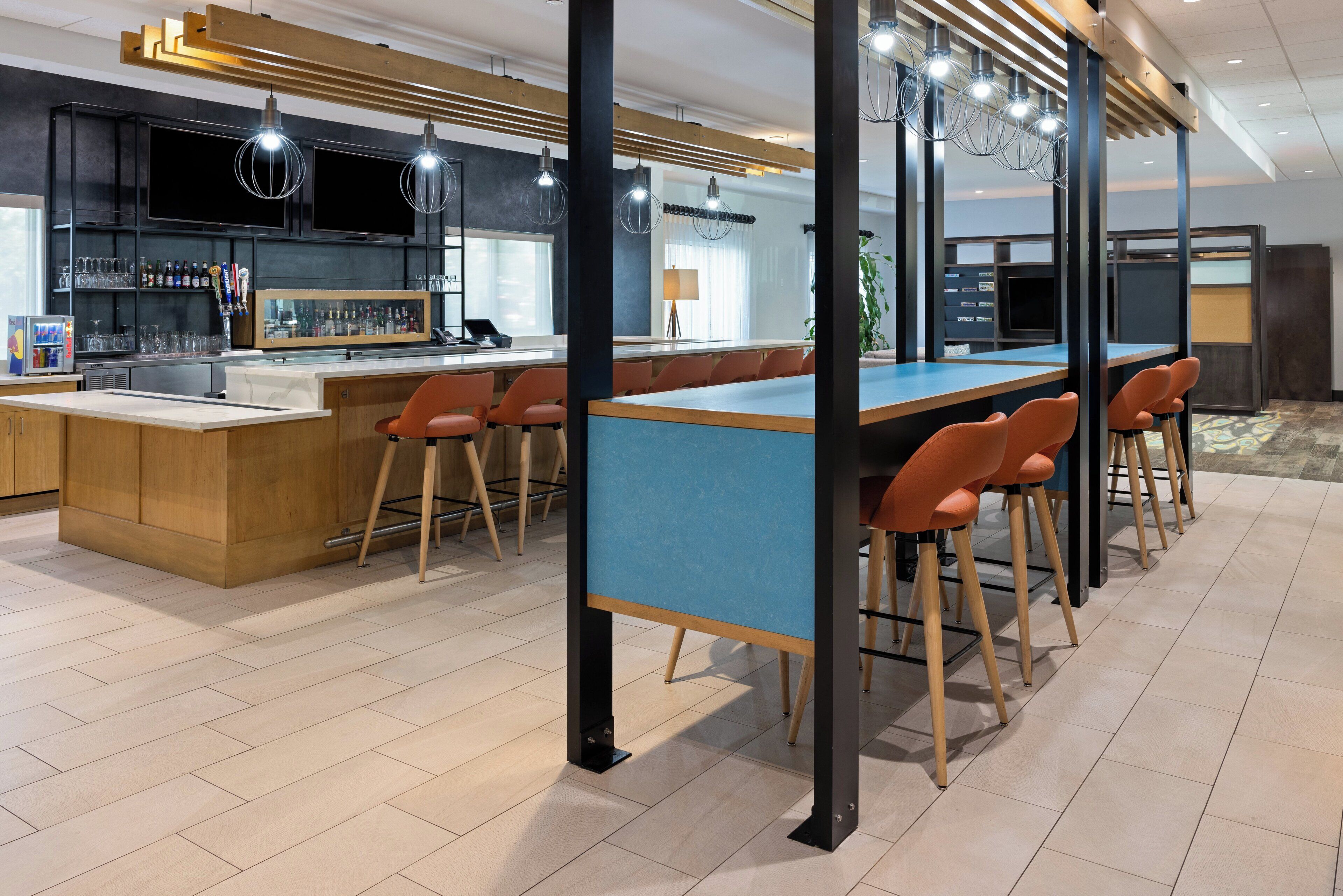 Una cocina moderna con una isla central, barra con taburetes y zona de estar con vista a la cocina.
