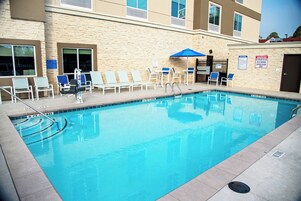 A swimming pool with lounge chairs and a lifeguard stand.