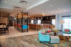 En modern hotellobby med en bardisk, sittgrupper och en väl synlig trappa.