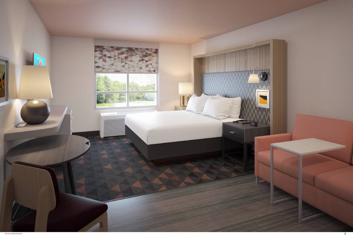 Ein Hotelzimmer mit Bett, Schreibtisch, Stuhl und einer Couch.