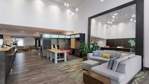 A modern hotel lobby with a large seating area, a reception desk, and a large mirror reflecting the space. - Holiday Inn & Suites Savannah Airport - Pooler by IHG (Pooler)