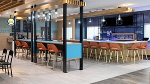 Eine moderne Bar mit einer langen Theke, mehreren Barhocker und Deckenleuchten.