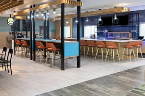 A modern bar area with a long counter, multiple bar stools, and overhead lighting. - Holiday Inn & Suites Savannah Airport - Pooler by IHG (Pooler)