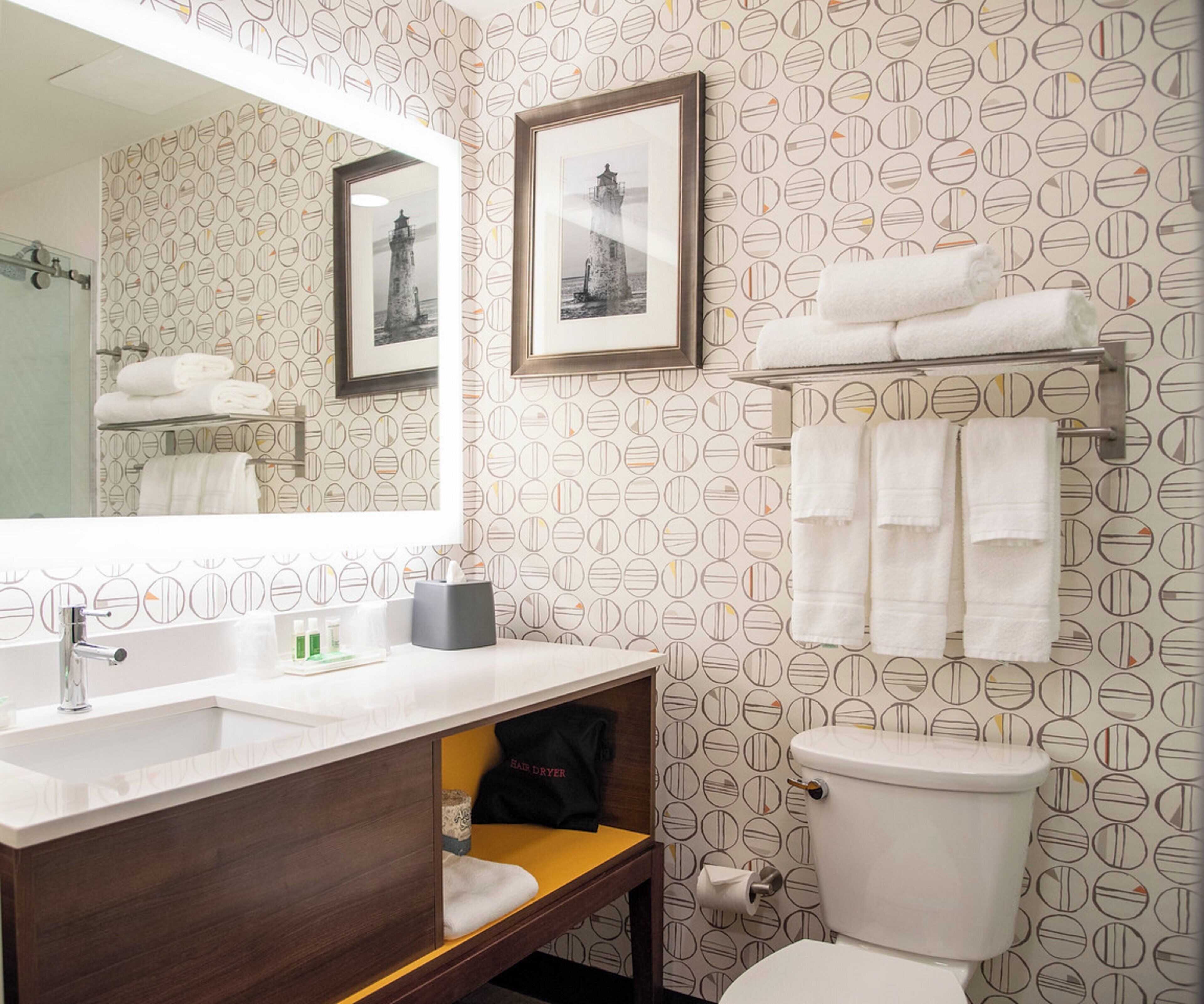 A bathroom with a mirror, sink, toilet, and towel rack.