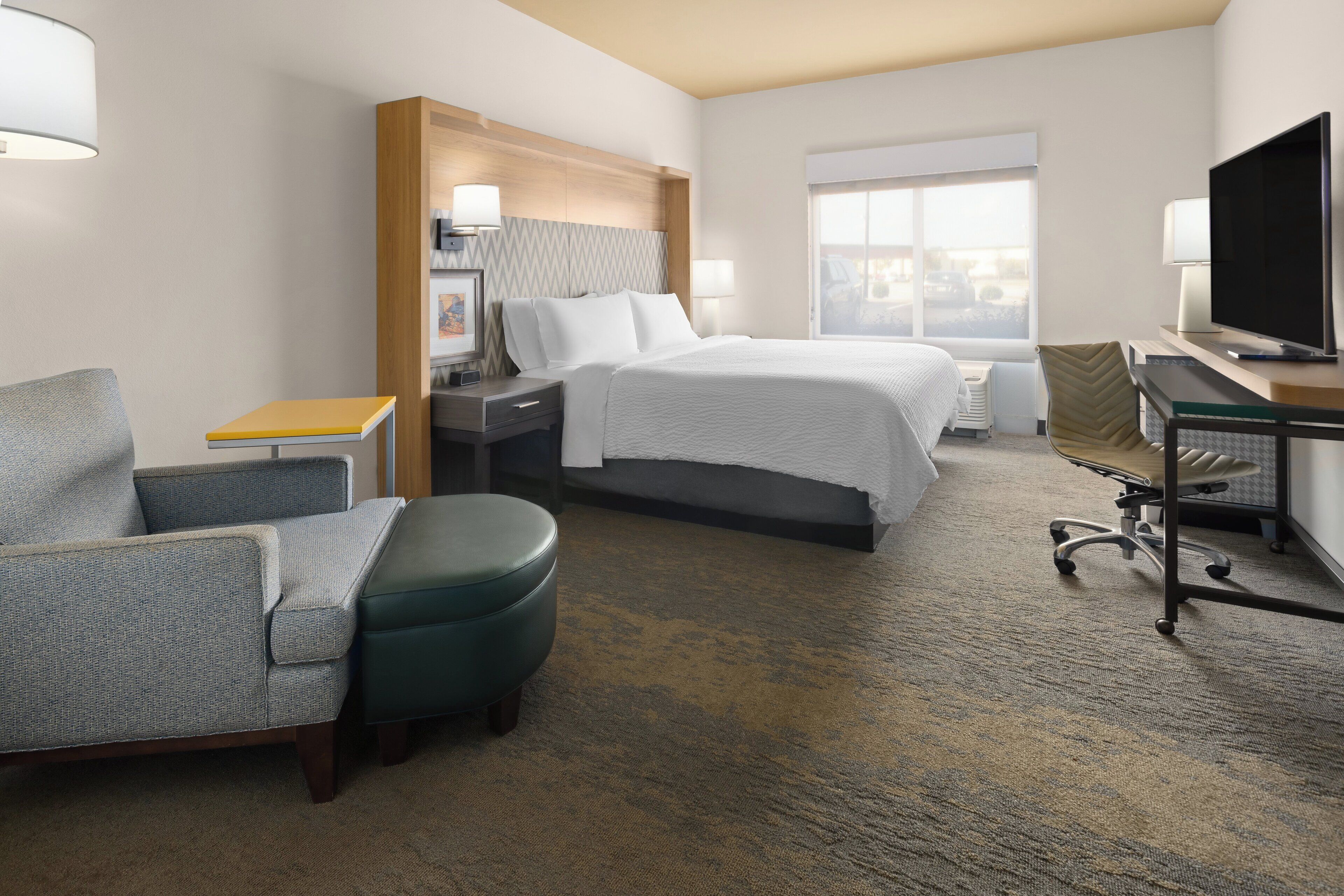 A hotel room with a bed, a desk, a chair, and a television.