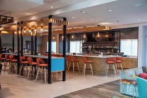 A modern bar area with multiple seating options, a bar counter, and a variety of bottles.