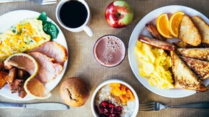 A breakfast setting with plates of eggs, bacon, toast, and fruit, along with a cup of coffee and a glass of juice. - Holiday Inn Express & Suites Springfield North by IHG (Springfield)