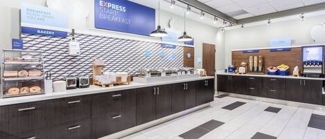 A modern breakfast area with a bakery section, a self-serve hot food station, and a cereal and fruit bar.