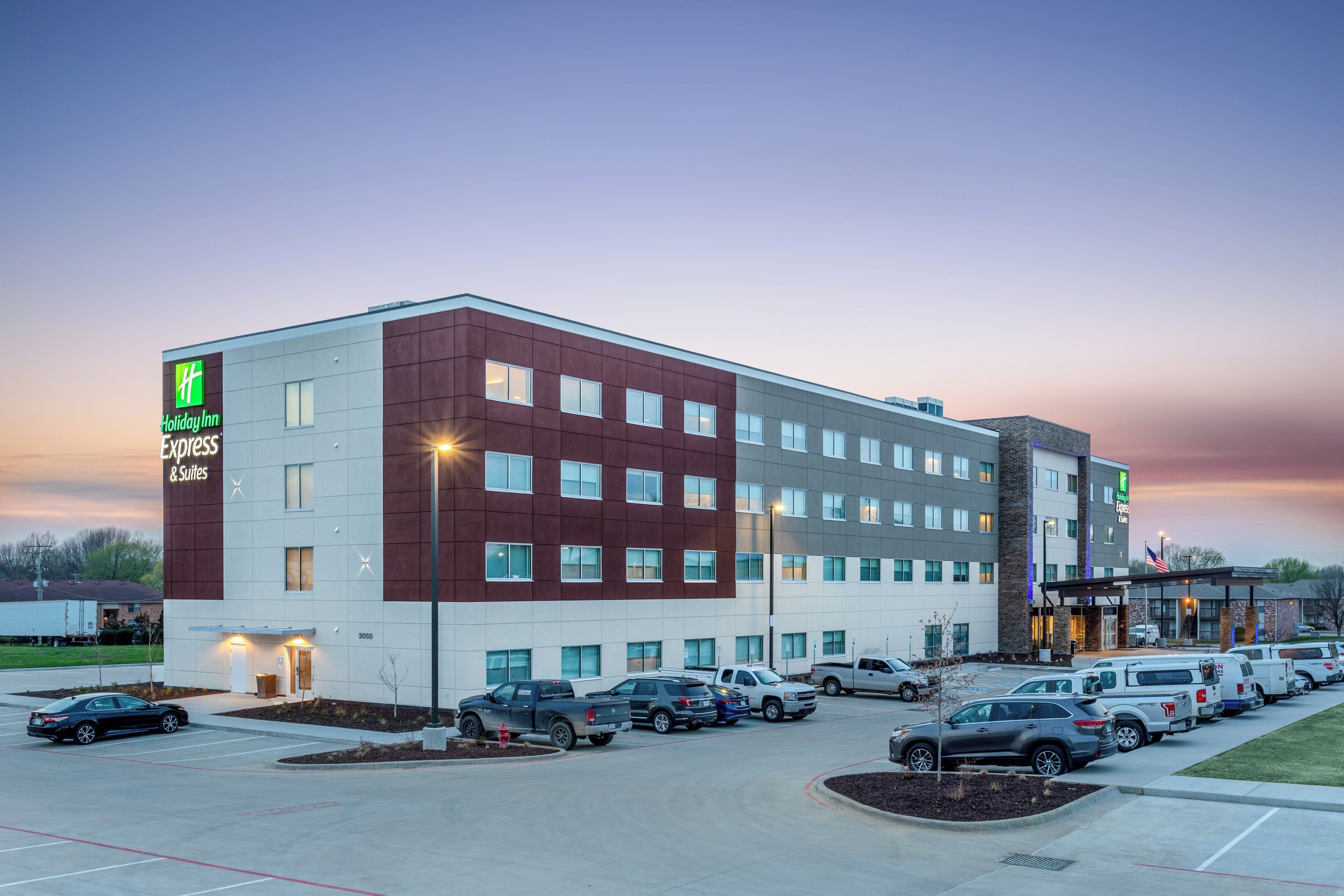 Holiday Inn Express & Suites -hotelli, jossa on pysäköintialue ja useita ajoneuvoja.