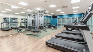 A gym with treadmills, weight machines, and exercise mats.