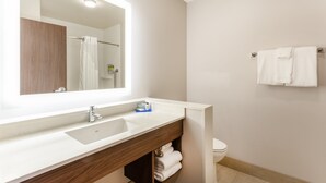 A modern bathroom with a large mirror, a white sink, and a wooden vanity. - Holiday Inn Express & Suites Springfield North by IHG (Springfield)