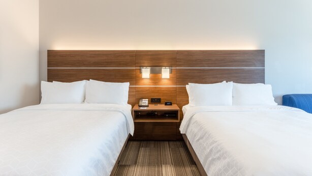 A hotel room with two beds, a wooden headboard, bedside tables with lamps, and a small nightstand. - Holiday Inn Express & Suites Springfield North by IHG (Springfield)