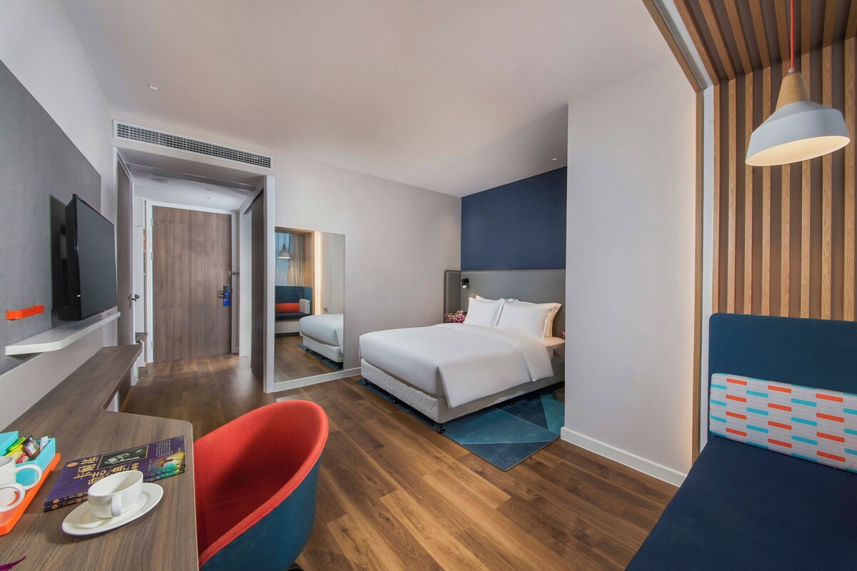 Una habitación de hotel con cama, escritorio, silla, televisor y baño.