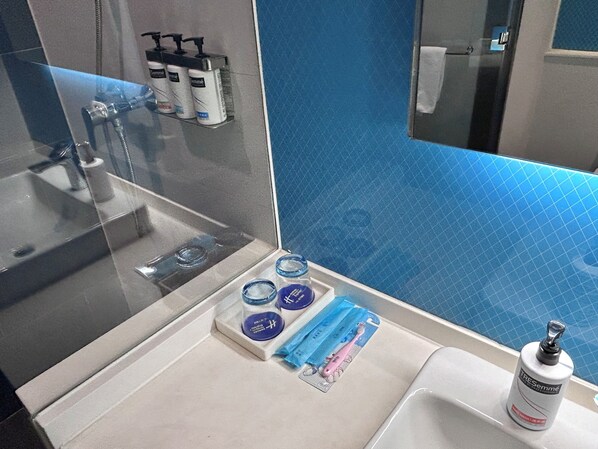 A bathroom with a glass shower enclosure, a sink, and toiletries on the counter. - Holiday Inn Express Shanghai Xuhui Binjiang by IHG (Shanghai)