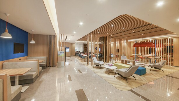 Un hall d’entrée spacieux, doté d’espaces détente, d’un comptoir d’accueil et d’un design moderne agrémenté d’éléments en bois.