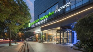 Un hôtel Holiday Inn Express doté d’une façade moderne en verre, d’une entrée bien visible et d’un éclairage extérieur soigné.