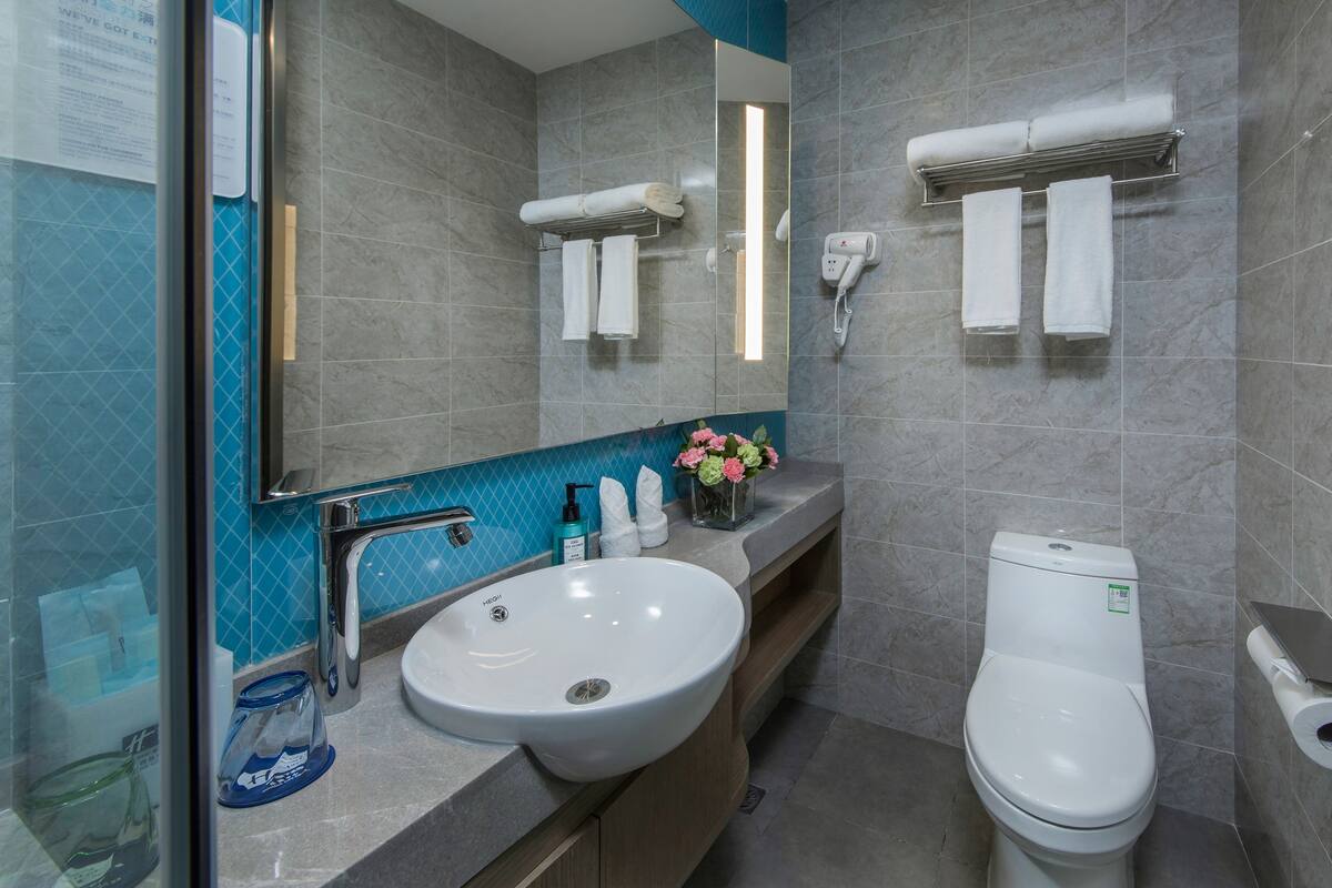A modern bathroom with a sink, toilet, and towel racks.