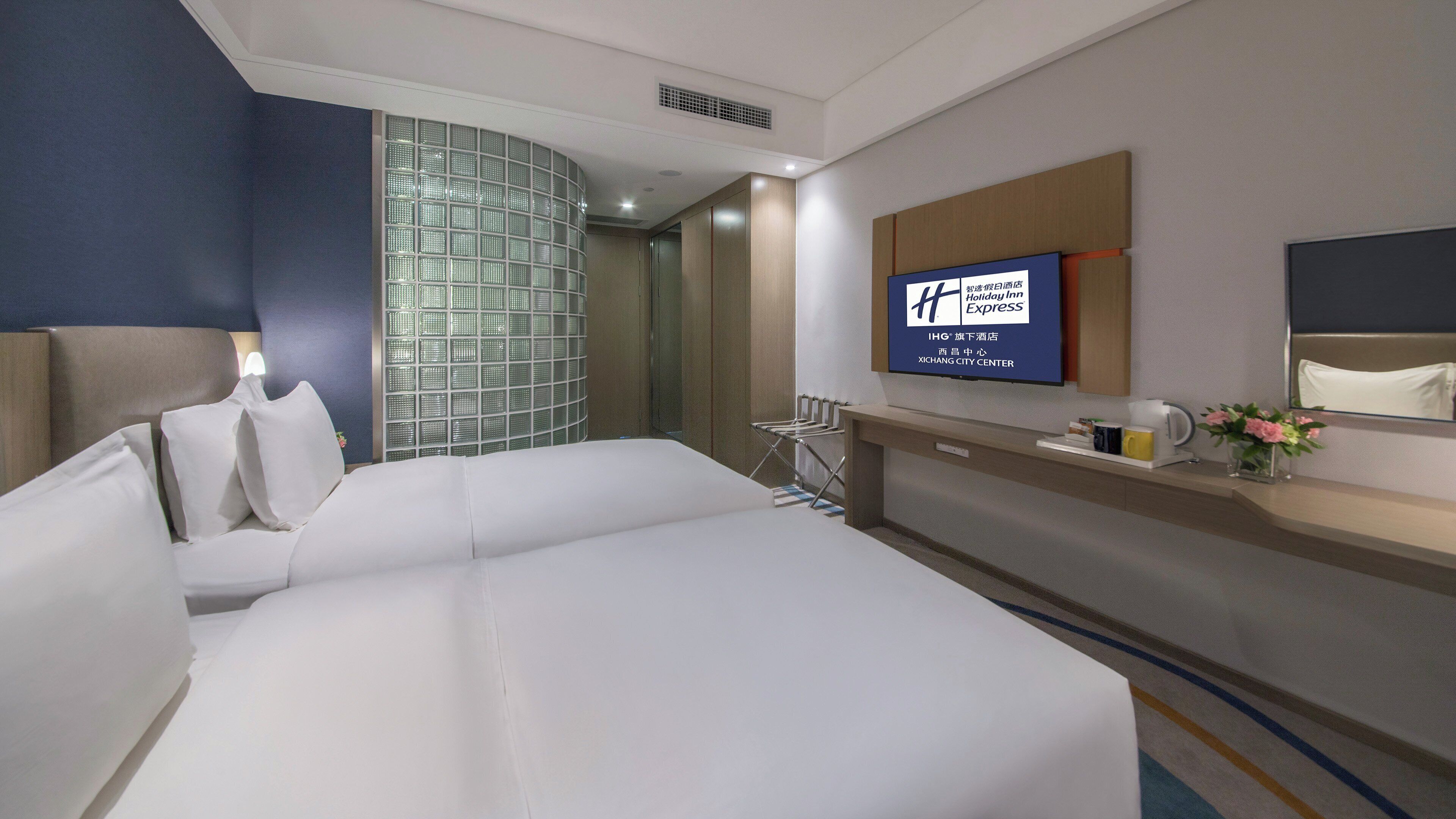 Habitación de hotel con cama, televisión, baño y vistas al centro de la ciudad.