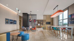 Un moderno vestíbulo de hotel con una recepción, zonas de estar y un amplio ventanal con vistas a la ciudad.