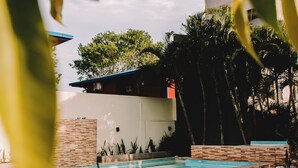 A modern outdoor pool area with a brick wall and a white building in the background. - Altos del Iguazu Hotel (Puerto Iguazú)